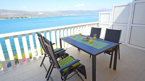 Un balcon avec une table dressée pour deux personnes, donnant sur une étendue d’eau.