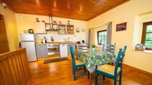 Eine Küche mit Holzausstattung, einem Kühlschrank, einem Herd und einem Esstisch mit Stühlen.