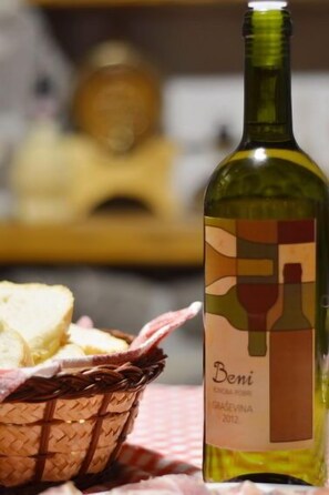 Una botella de vino con etiqueta, una cesta de pan y un fondo desenfocado.