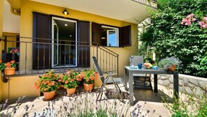 Ein gelbes Gebäude mit Balkon, Blumentöpfen und einem Tisch mit Stühlen.
