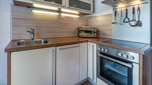 Et moderne køkken med indbygget ovn, mikroovn og en stålvask.