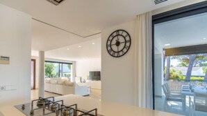 Une cuisine moderne dotée d’un îlot central, d’une grande horloge murale et donnant sur un espace patio extérieur.