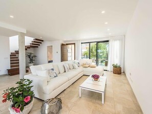 Un salon moderne avec un canapé blanc, une table basse et un escalier.