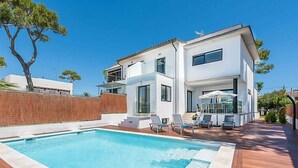 Une maison moderne à deux étages dotée d’une piscine, d’un espace salon extérieur et d’une terrasse en bois.