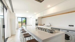 Une cuisine moderne dotée d’un grand îlot central, d’un four encastré et d’un lave-linge.