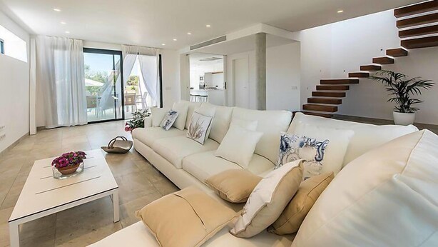 Un salon moderne avec un canapé, une table basse et un escalier.