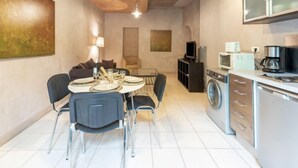 Un espace de vie compact comprenant un coin repas, un canapé, une télévision, un lave-linge et une kitchenette.