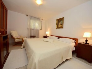 Une chambre d’hôtel avec un grand lit, deux tables de chevet avec des lampes, une chaise, une petite table et un tableau au mur.