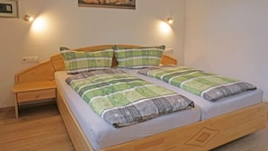 A double bed with striped bedding, a wooden headboard, and bedside lamps. - Apartment Susi by Interhome (Flirsch)