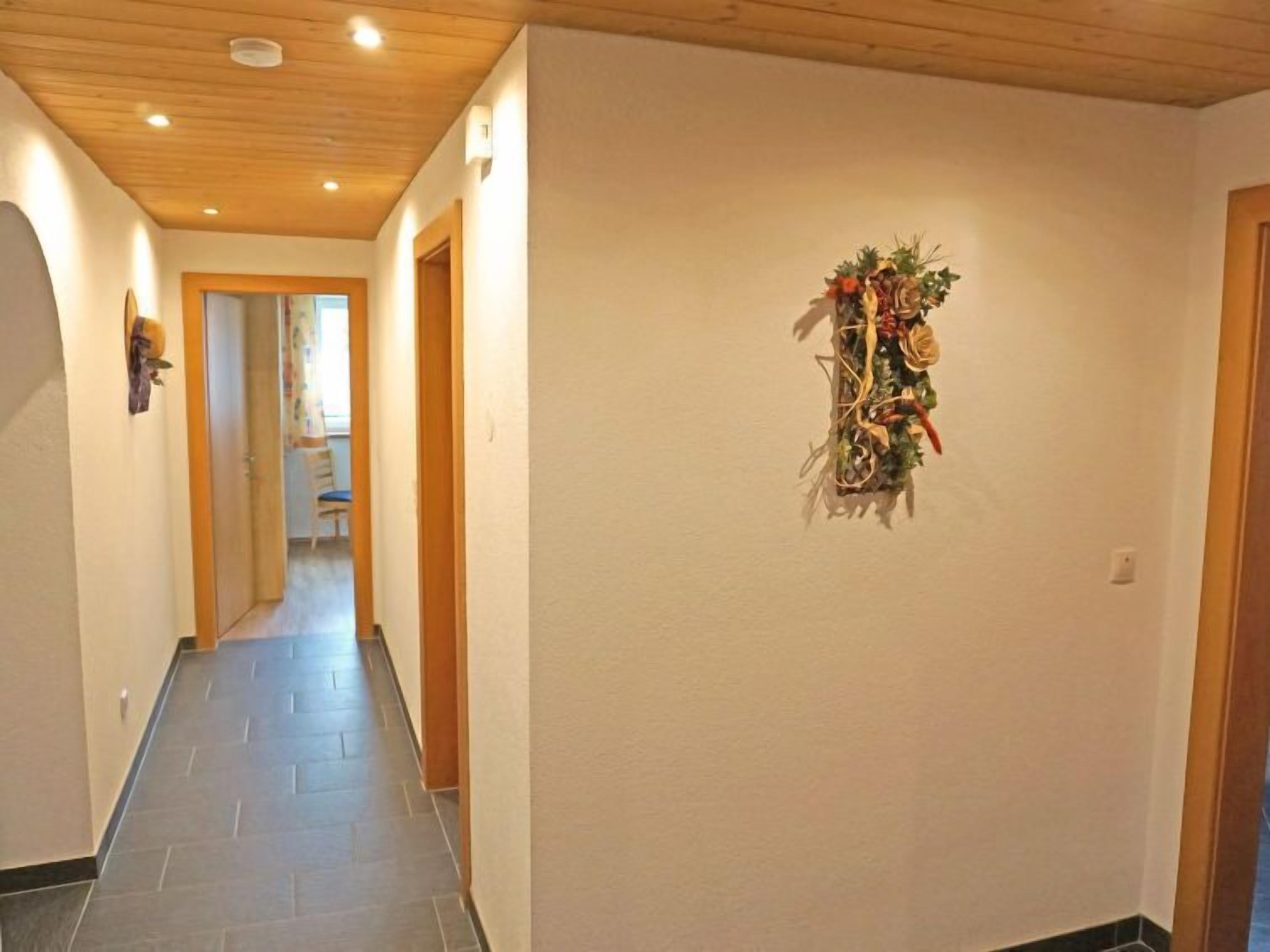 Un couloir avec un plafond et des murs en bois, un sol carrelé et une guirlande décorative accrochée au mur de droite.