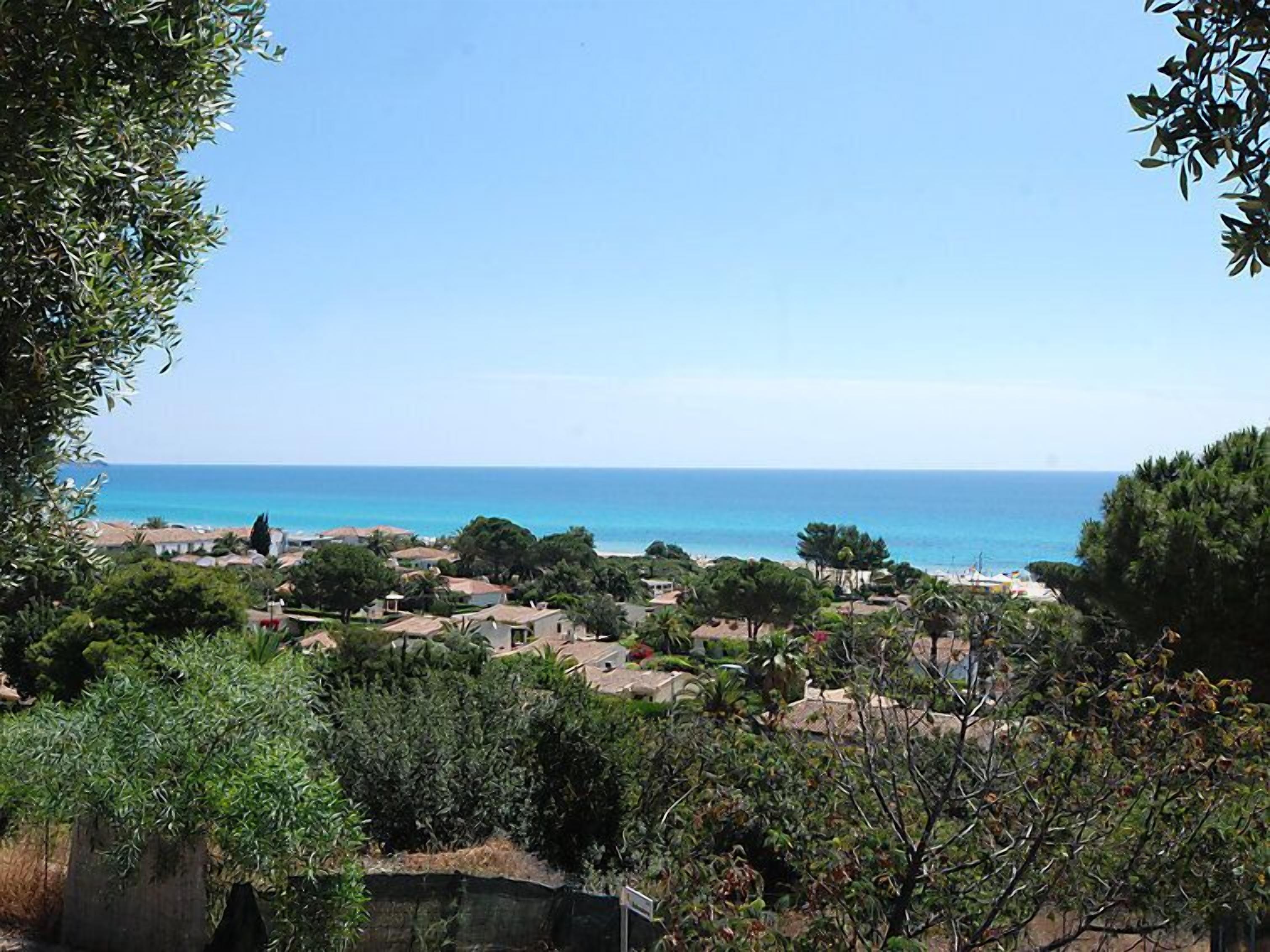 A coastal village with houses and greenery, overlooking the sea.