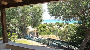 Ein überdachter Außenbereich mit Blick auf eine Küstenlandschaft, Bäume und einen fernen Strand.