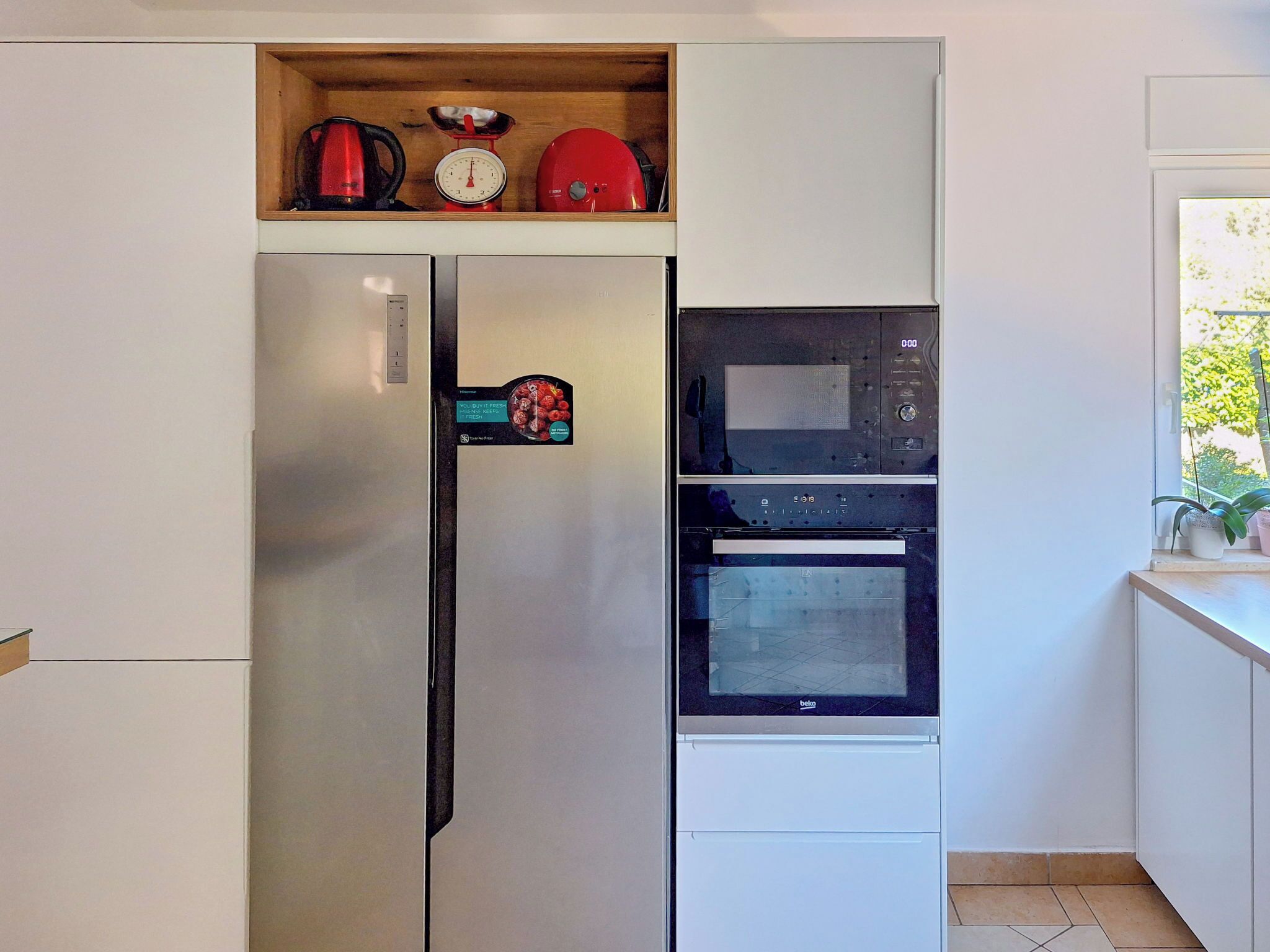 A kitchen with a stainless steel refrigerator, a microwave, and a built-in oven.