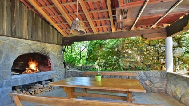 An outdoor patio with a stone fireplace, wooden benches, and a table. - Vacation home Zorica by Interhome (Opatija/Mihelici)