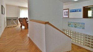 A hallway with a wooden floor, a wooden staircase, and a chair in the background. - Vacation home Zorica by Interhome (Opatija/Mihelici)