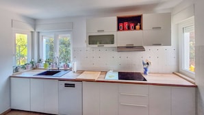 A modern kitchen with a central island, built-in dishwasher, and a window providing natural light. - Vacation home Zorica by Interhome (Opatija/Mihelici)