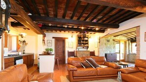 Un salón acogedor con un sofá de cuero marrón, techo de madera y chimenea de piedra.