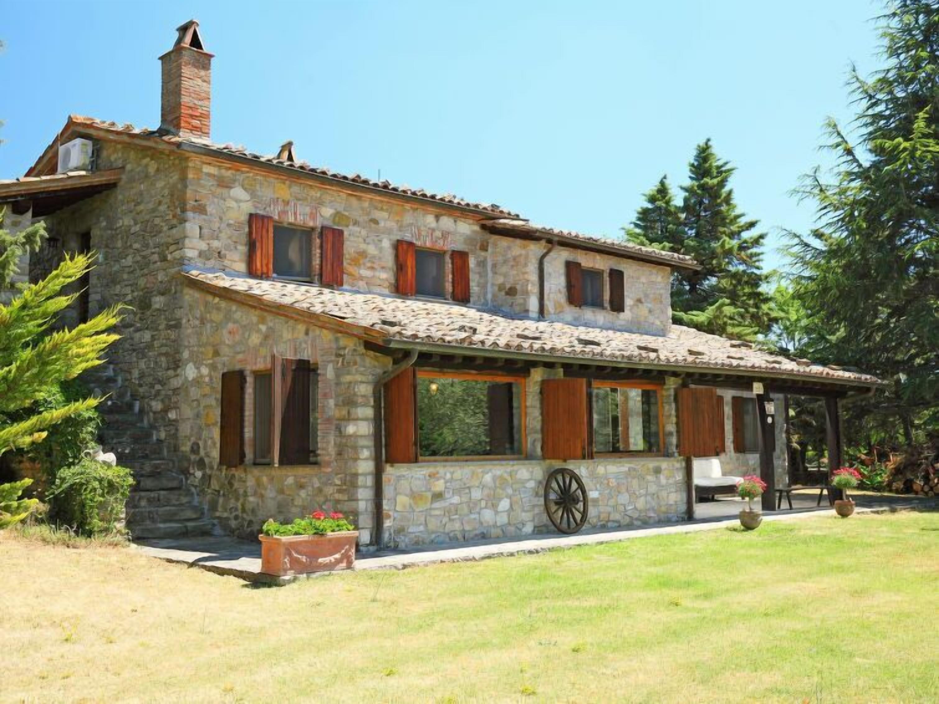 Una casa de piedra con techo de tejas, contraventanas de madera y una chimenea.