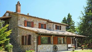 Una casa de piedra con techo de tejas, contraventanas de madera y una chimenea.