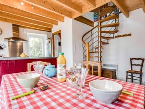 A kitchen with a red and white checkered tablecloth, a wooden spiral staircase, and a window with a view of greenery. - Courdiec by Interhome (Carnac)