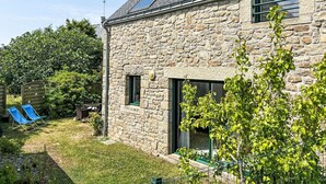 Ein Steinhaus mit einem geneigten Dach, einem kleinen Fenster und einer Tür.