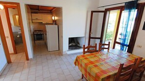 A compact living space with a dining area, kitchenette, and a fireplace.