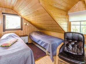 A room with two beds, a nightstand, a leather chair, and a window. - Lakunlahti by Interhome (Juuka)