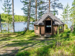 A small cabin with a sloped roof, situated in a forested area near a body of water. - Lakunlahti by Interhome (Juuka)