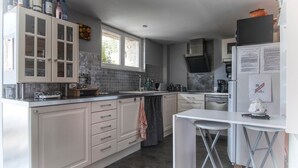 A modern kitchen with white cabinetry, a central island, and a built-in oven. - “Intimacy” cottage for 2 people (without SPA) (Léguillac-de-l'Auche)