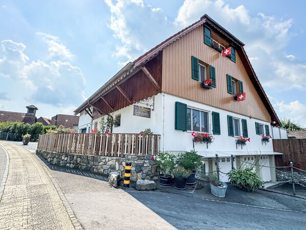 Un edificio de estilo chalete tradicional con techo inclinado, fachada de madera y contraventanas verdes.