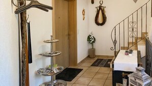 A hallway with a wooden door, a metal staircase, a small table with a white tablecloth, and a decorative lantern.