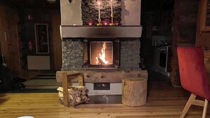 A cozy living room with a stone fireplace, a red chair, and a coffee table with a mug.