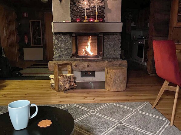 A cozy living room with a stone fireplace, a red chair, and a coffee table with a mug.