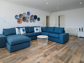 Una sala de estar moderna con un sofá seccional azul, una mesa de centro redonda y una colección de platos decorativos en la pared.