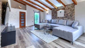 A modern living room with a grey sectional sofa, a black coffee table, and a stone accent wall. - Vacation home Darija by Interhome (Novigrad (Istra))