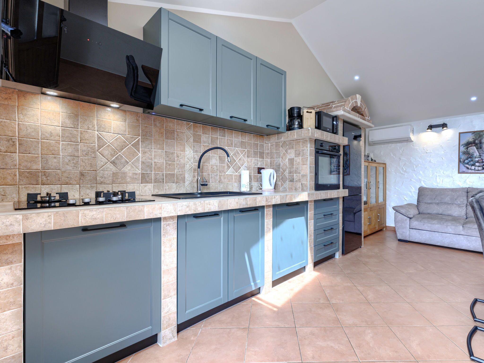 A modern kitchen with blue cabinets, a gas stove, and a built-in oven.