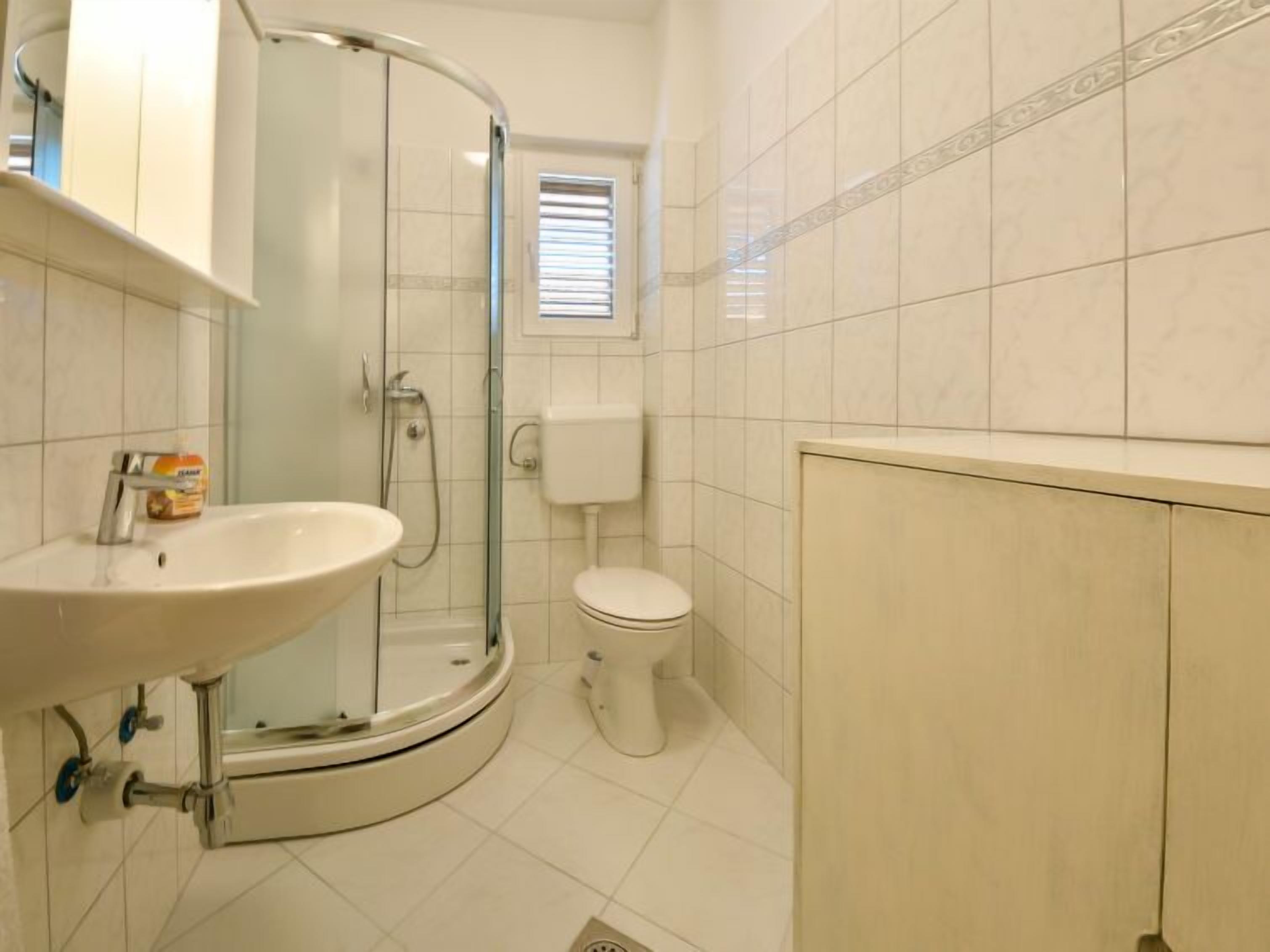 A modern bathroom with a glass shower enclosure, a toilet, and a sink.