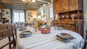 A dining area with a large table set for six, wooden cabinets, and a chandelier. - Saint Ideuc by Interhome (Saint Malo)