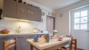 A kitchen with a wooden table, chairs, and cabinets. There is a window with a view of the outside. - Saint Ideuc by Interhome (Saint Malo)