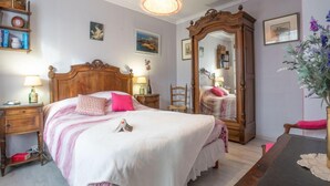 A bedroom with a large bed, wooden headboard, bedside tables with lamps, a mirror, and a dresser. - Saint Ideuc by Interhome (Saint Malo)