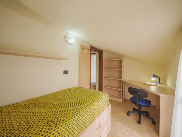 A small bedroom with a bed, a desk, a chair, and a wardrobe.