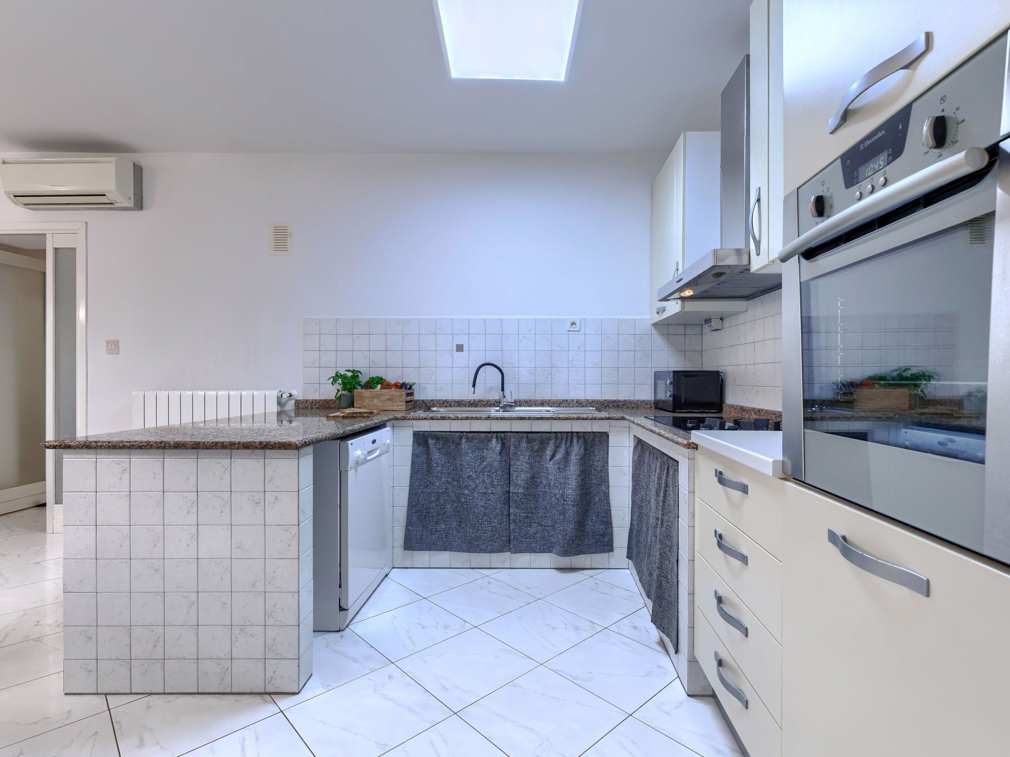 A modern kitchen with a built-in island, white tiled backsplash, and stainless steel appliances.