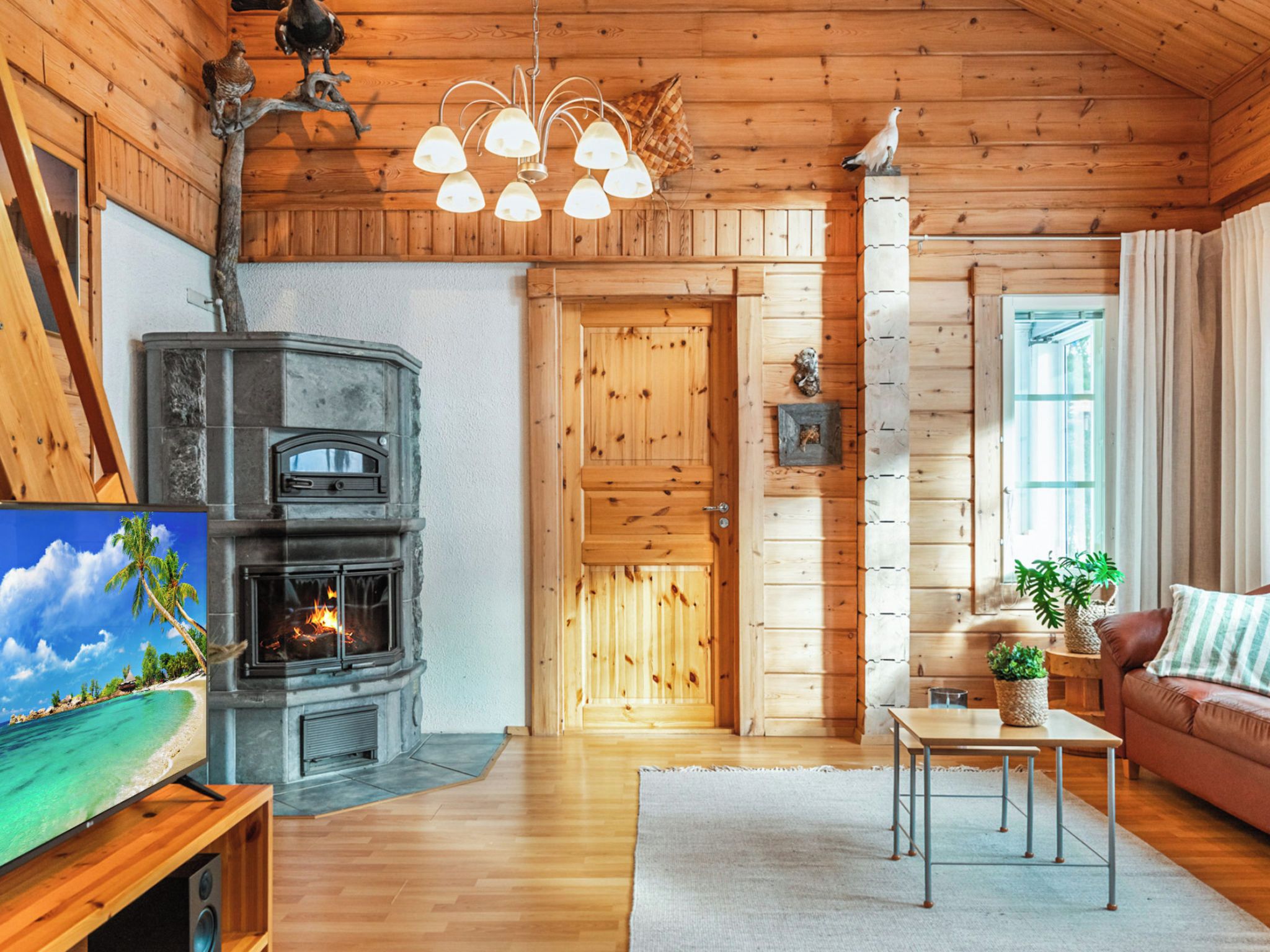 L’intérieur d’un chalet accueillant, avec une cheminée, des murs en bois, un canapé et une table agrémentée d’une plante.
