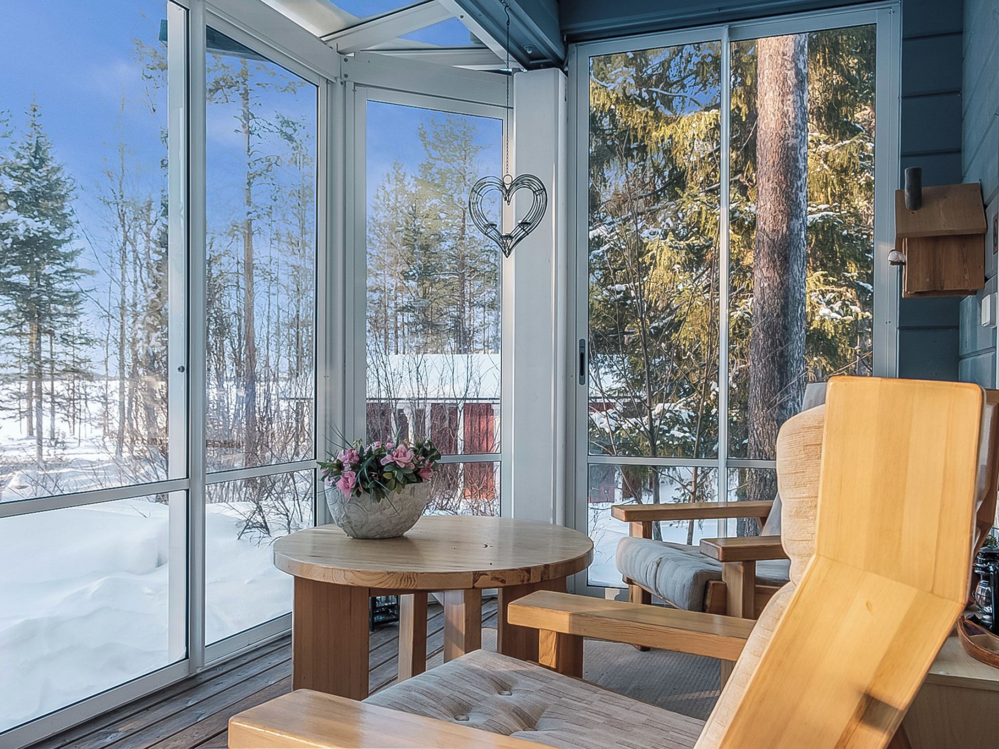 A sunroom with a view of a snowy landscape and trees.