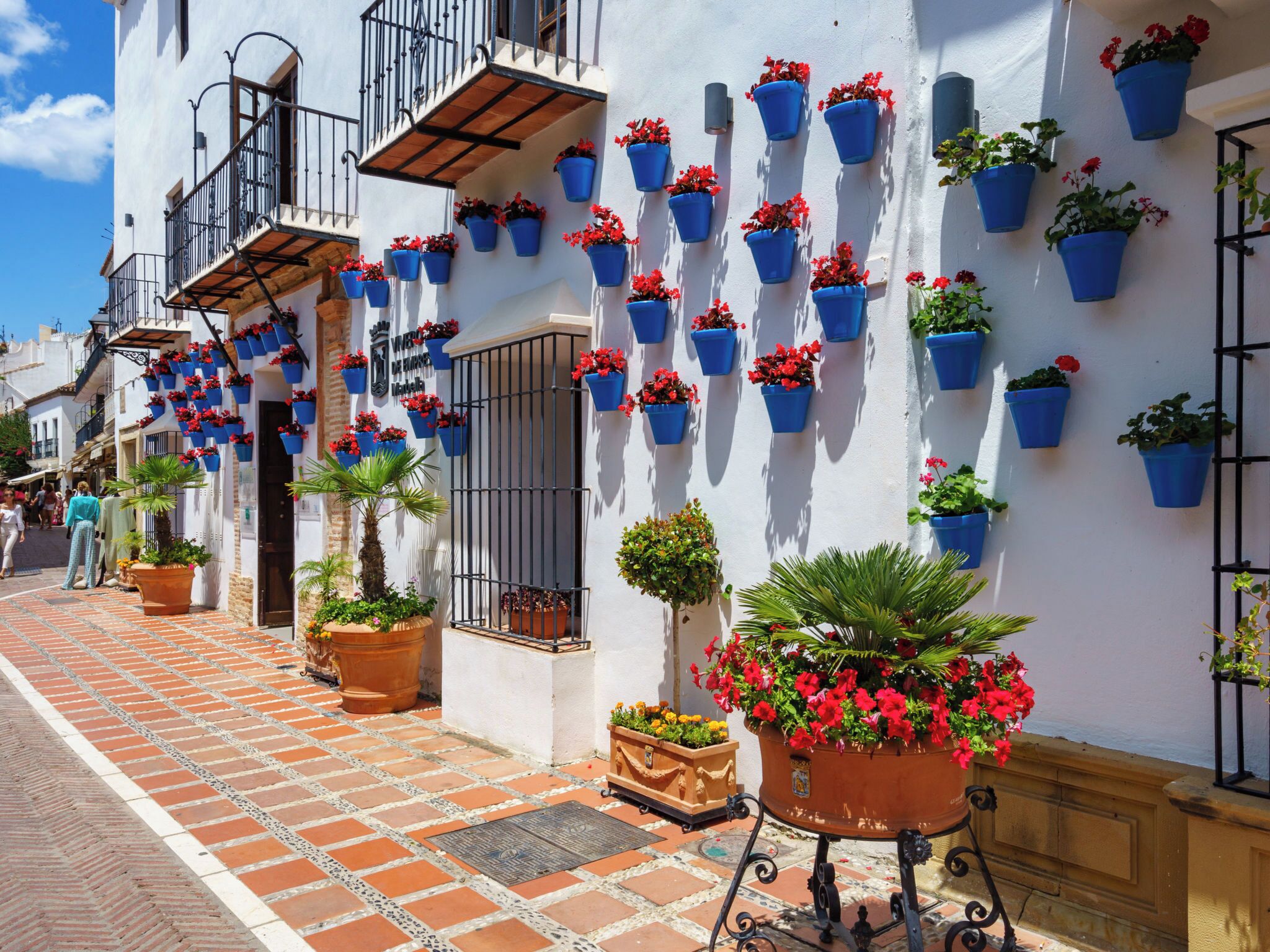 A building with multiple balconies, each adorned with blue hanging flower pots.