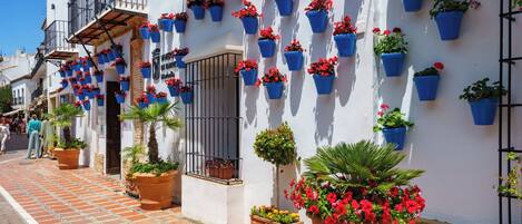 A building with multiple balconies, each adorned with blue hanging flower pots.