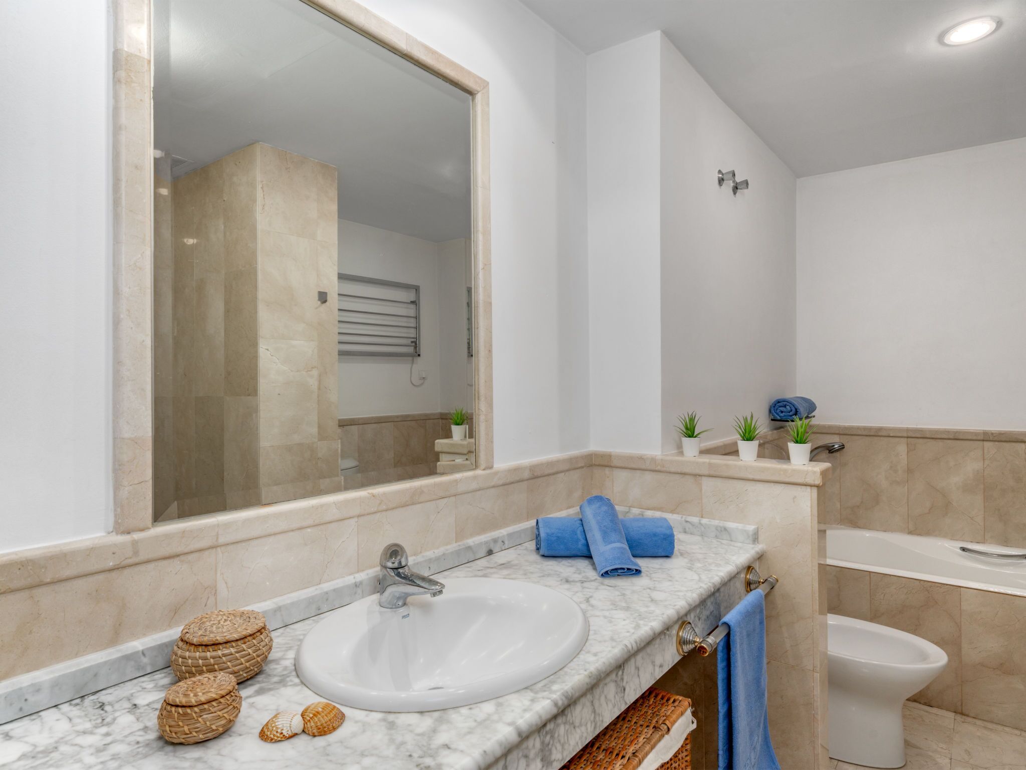 A bathroom with a large mirror, a sink, a toilet, and a shower area.