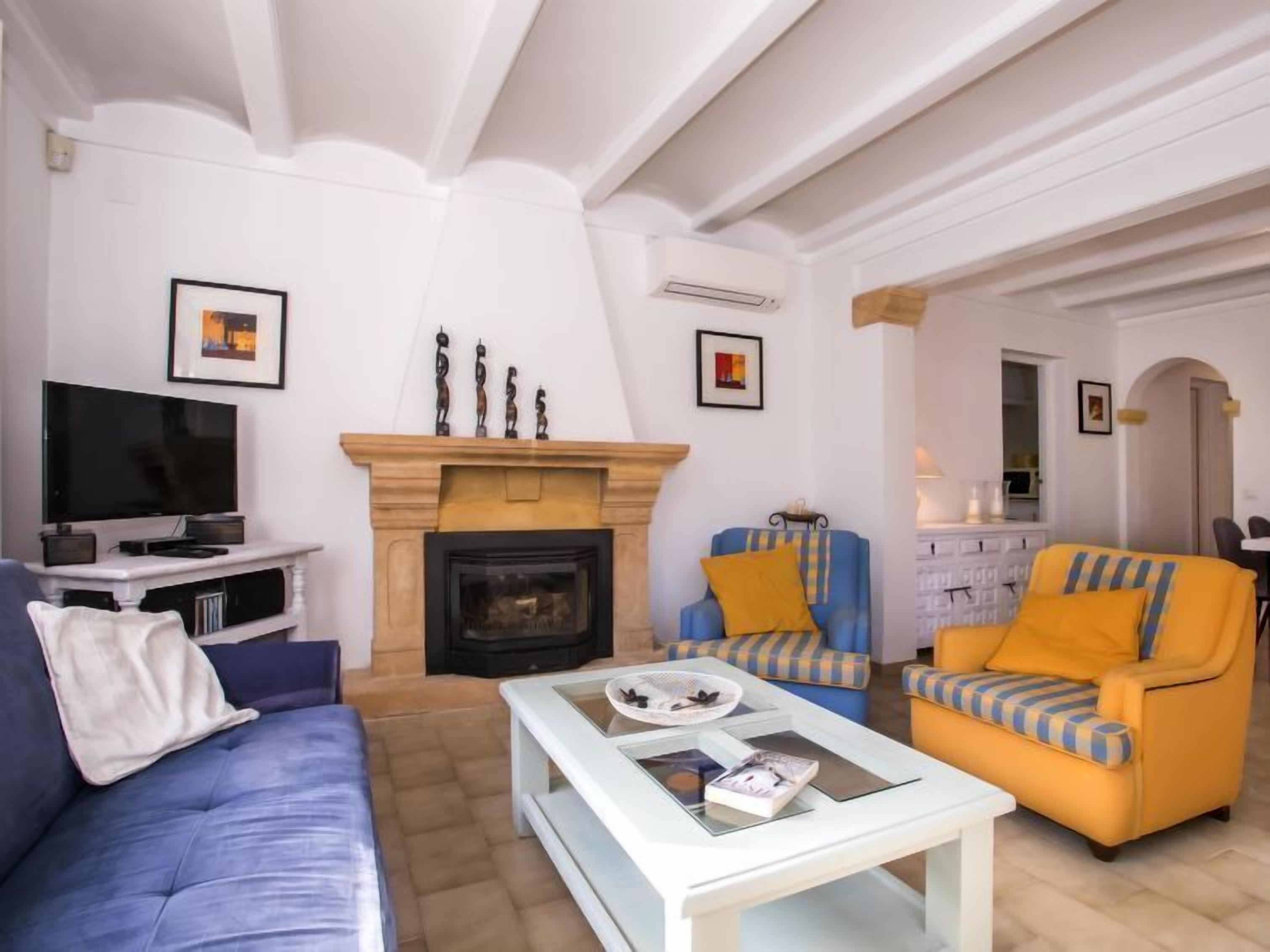 A living room with a fireplace, a sofa, a chair, and a television.