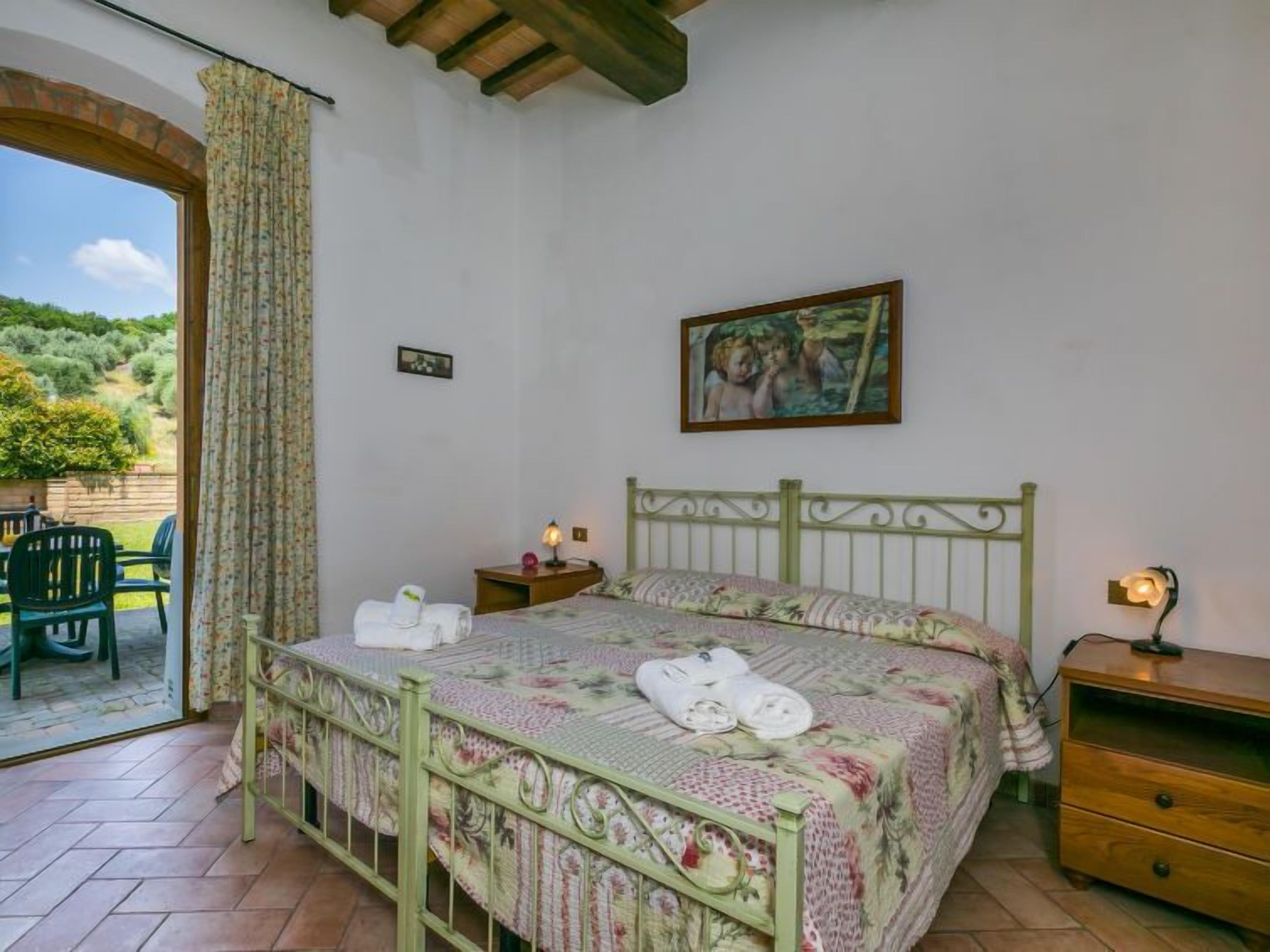 Un dormitorio con cama, mesita de noche, cómoda y vistas al exterior.
