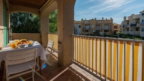 Un balcon avec une table préparée pour le petit-déjeuner, donnant sur un quartier résidentiel.